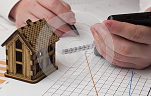 Wooden house in the graphs and male hand with phone