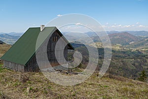 Wooden house with green roof in the mountains