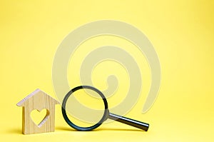 Wooden house with a heart and a magnifying glass. The concept of search for affordable housing. A dream is to buy a house.