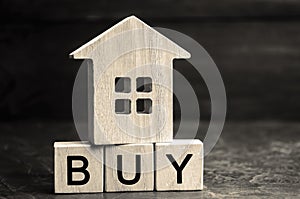 Wooden house and the inscription ` Buy ` on wooden blocks. The concept of buying property. Purchase a home, apartment, real estate