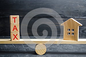 Wooden house with the inscription `Tax` on the scales. Taxes on real estate, payment. Penalty, arrears. Register of taxpayers for