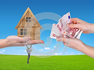 Wooden house with key and Euro money in hands