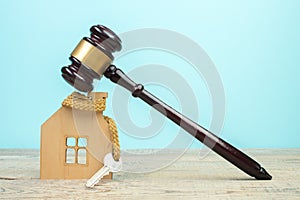 Wooden house, keys and judge's gavel on a wooden table. Symbol of mortgage, dilapidated housing, auction.