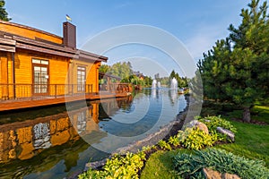 A wooden house is located above the lake with fountains in the park. mezhigriya Ukraine