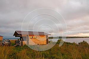 Wooden house from log house on lake shore at sunset in summer, Karelia, Russia