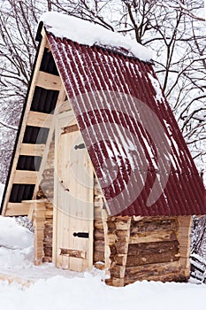 Wooden house from log, with red roof in winter forest