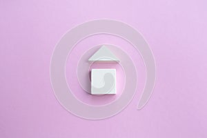 Wooden house made of wooden geometric details on a pink background. Family home concept