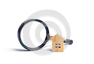 Wooden house and magnifying glass on a white background. Buying and selling real estate, building new buildings, offices and homes