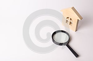 Wooden house and a magnifying glass on a white background. The concept of finding a house, buying or renting an apartment. Realtor