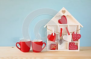 Wooden house with many hearts next to coffee cups