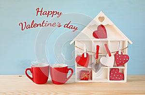 Wooden house with many hearts next to coffee cups