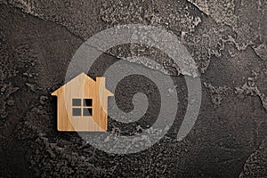 Wooden house model on a black marble background.