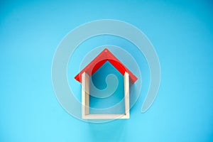 Wooden house model on blue background.