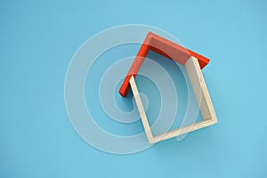 Wooden house model on blue background.