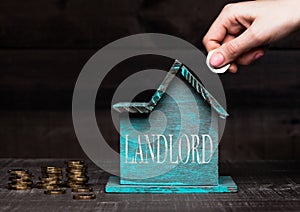 Wooden house model with coins next to it and hand