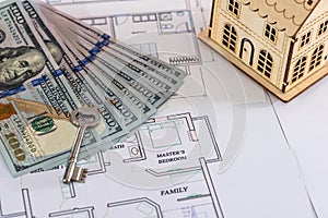 Wooden house model with dollars and key on the plan