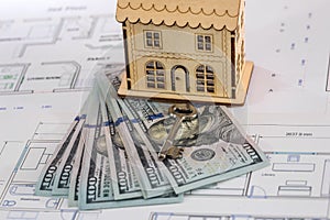 Wooden house model with dollars and key on the plan