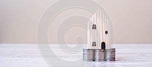Wooden house model over coins stack on table background. Business, Investment, Money Saving, Real Estate and Retirement plan
