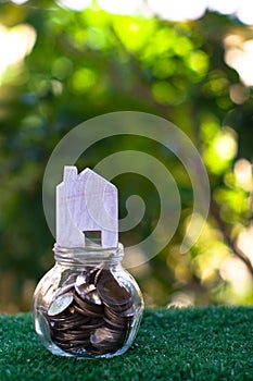 Wooden house model on top of glass jar which full of coins. Home mortgage and property investment concept