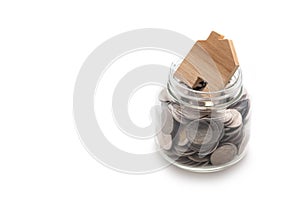 Wooden house modeled on many coins in a glass jar photo
