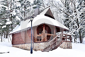 Wooden house in mountain in winter time. Log cabin in forest alone in wilderness. Wooden house with a wooden roof against