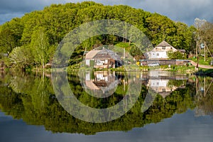 Wooden house near lake, forest reflected on water