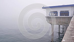 Wooden house on piles in water, Ocean Beach pier, foggy California coast, USA.