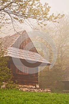 Wooden house in Podsip mountain village during misty morning in Sipska Mala Fatra mountains