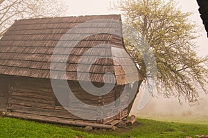 Wooden house in Podsip mountain village during misty morning in Sipska Mala Fatra mountains