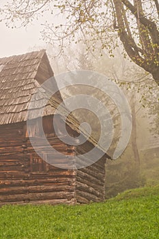 Wooden house in Podsip mountain village during misty morning in Sipska Mala Fatra mountains