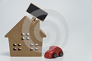 Wooden house, red car toy and small black board with white background and selective focus