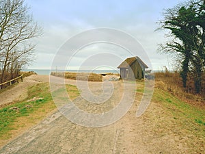 Wooden house at sand dune, close to sea. Walking path to the beach.