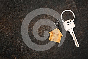 Wooden house shaped keychain and key on stone background. Free space