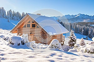 Wooden house in snowy mountains on sunny clear day. European village in Alps in skiing season. Winter nature landscape of snowy