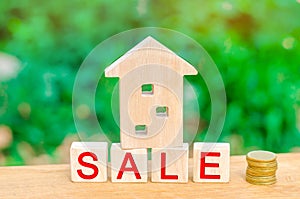 Wooden house and stack of coins with the inscription `sale`. sale of property, home, real estate. affordable housing.