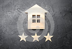 Wooden house and three stars on a gray background. Rating of houses and private property. Buying and selling, renting apartments.