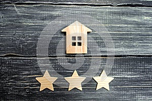 Wooden house and three stars on a gray background. Rating of houses and private property. Buying and selling, renting apartments.