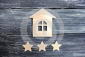 Wooden house and three stars on a gray background. Rating of houses and private property. Buying and selling, renting apartments.
