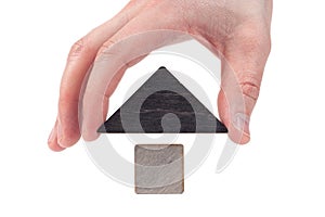 Wooden house toy blocks isolated white background, little wooden home with hand. The concept of buying and selling real estate,