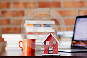 Wooden house toy on a table with books