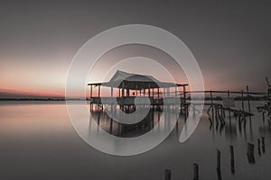 wooden house on the water as the sun sinks