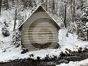 Wooden house in the winter forest. An old wooden building. A log house in the middle of a snowy forest