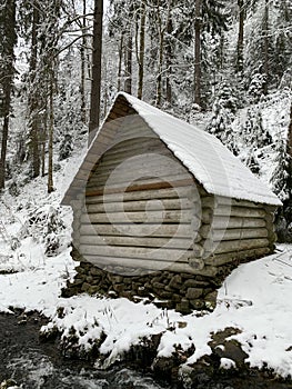 Wooden house in the winter forest. An old wooden building. A log house in the middle of a snowy forest