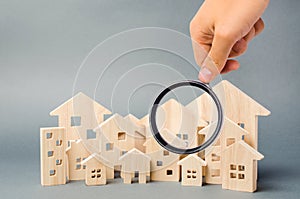 Wooden houses and magnifying glass. Property valuation. Home appraisal. Choice of location for the construction. House searching photo