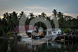 Wooden houses at pier with palmtree background in evening time in thailand