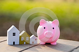 Wooden houses and piggy bank stands outdoors on a sunny day.