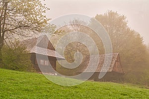 Wooden houses in Podsip mountain village during misty morning in Sipska Mala Fatra mountains