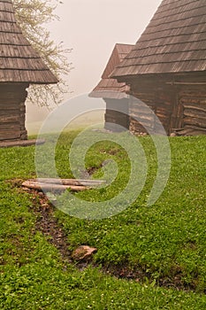 Wooden houses in Podsip mountain village during misty morning in Sipska Mala Fatra mountains