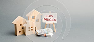 Wooden houses and a poster with the words Low Prices. The concept of reducing the value of real estate. Lower mortgage interest
