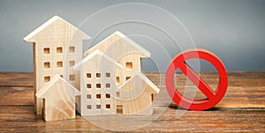 Wooden houses and a prohibition sign. Inaccessible and expensive housing. Restrictions and a ban on the construction of buildings photo